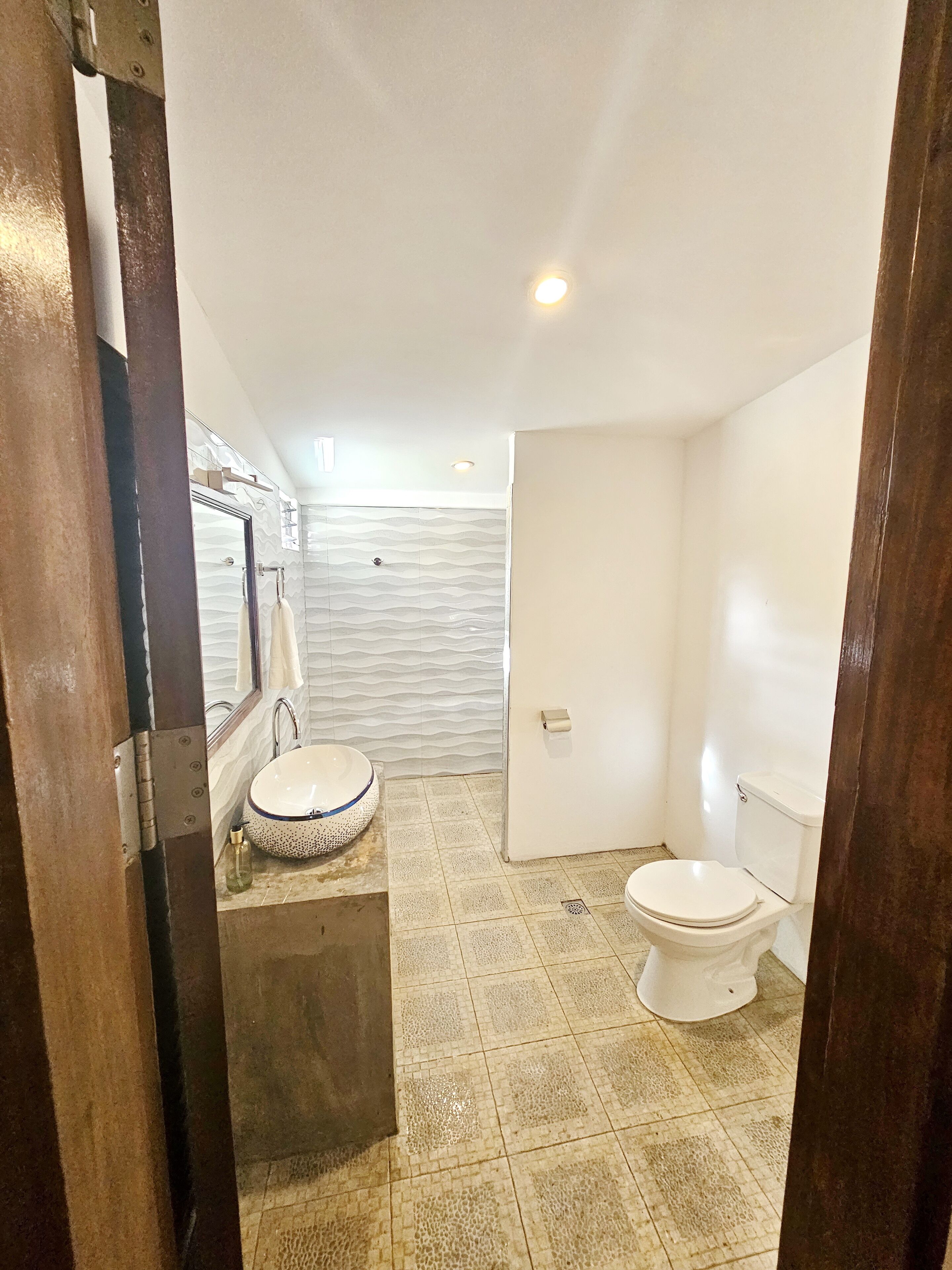 Un baño pequeño y funcional con un lavamanos blanco, un inodoro y una zona de ducha.