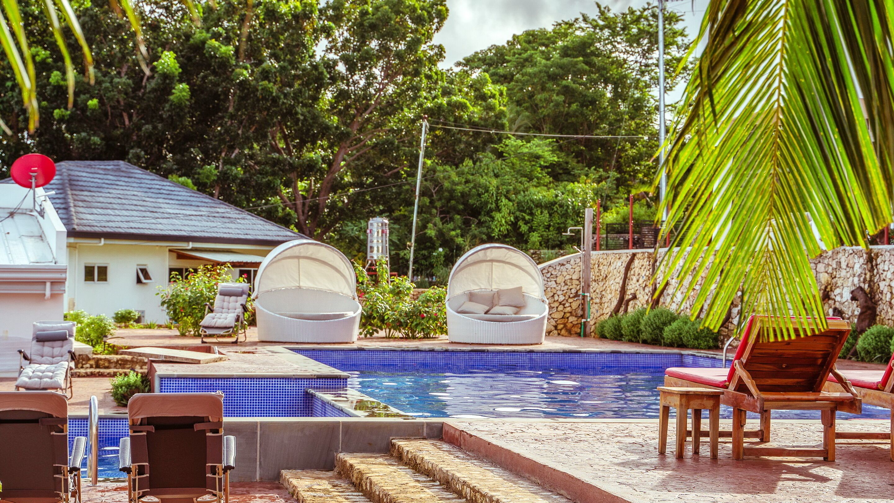 A swimming pool with lounge chairs and a covered seating area.