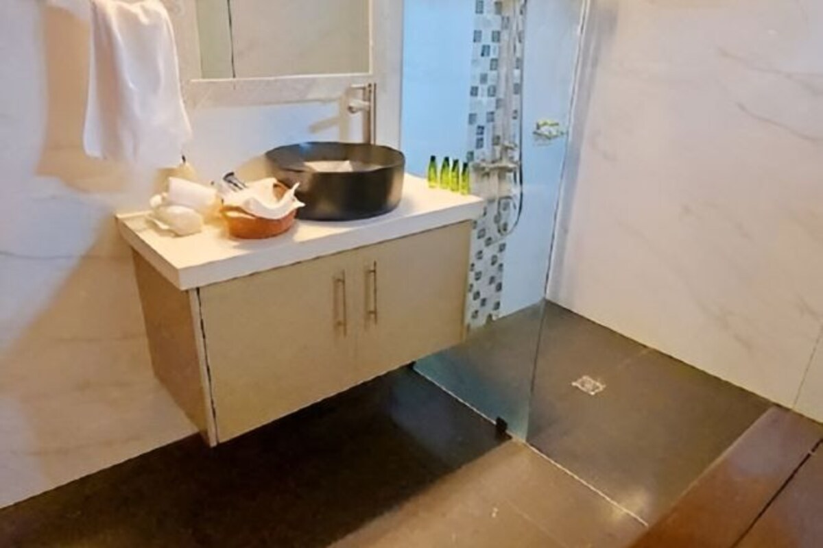 A bathroom with a modern sink, a mirror, and a shower area.