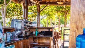 An outdoor café with a coffee machine, wooden tables, and a view of trees. - The Gabayan Riviera (Lazi)