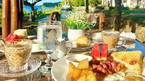 A breakfast table with a view of a tropical landscape, including palm trees and a body of water. - The Gabayan Riviera (Lazi)