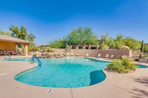 A pool area with lounge chairs and a covered seating area.