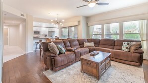 A spacious living room with a large sectional sofa, a wooden coffee table, and a ceiling fan. - Completely Remodel Condo, Sleep Number I-8 bed with adjustable firmness. (Cave Creek)