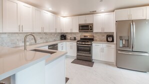 A modern kitchen with white cabinets, a stainless steel refrigerator, a microwave, a stove, and a sink. - Completely Remodel Condo, Sleep Number I-8 bed with adjustable firmness. (Cave Creek)