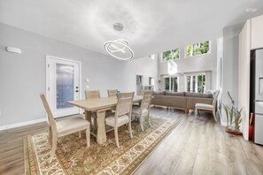 Eine moderne Küche mit Einbauofen, eine Essecke mit Holztisch und Stühlen sowie ein großes Fenster, das für natürliches Licht sorgt.