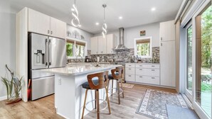 Een moderne keuken met een centraal eiland, roestvrijstalen apparatuur en een groot raam met uitzicht op de omgeving.
