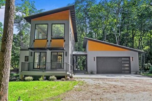 A modern two-story house with a large garage, surrounded by trees.