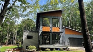 Een modern huis met twee verdiepingen, een groot raam, een kleine garage en een verzorgd gazon.
