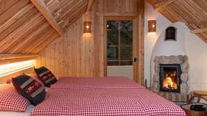 Un dormitorio acogedor con colcha a cuadros, chimenea de piedra y paredes de madera.