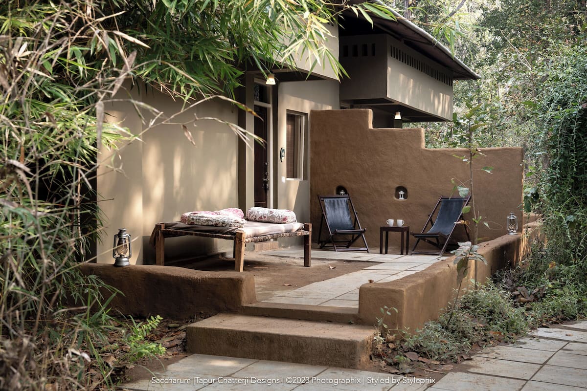 A rustic outdoor seating area with a sofa, two lounge chairs, and a small table.