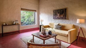 A cozy living room with a sofa, coffee table, and a painting on the wall. - Saccharum Safari Lodge (Baihar)