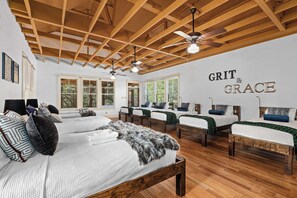 A room with a wooden ceiling, multiple beds, and a wall with 'GRIT & GRACE' text. - Grit&Grace Ranch - Private Resort Style Pool & Spa (Austin)