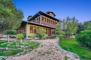 A two-story house with a front porch, a visible staircase, and a garden with a stone pathway. - Grit&Grace Ranch - Private Resort Style Pool & Spa (Austin)