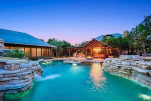 A resort with a swimming pool, stone walls, and a wooden structure. - Grit&Grace Ranch - Private Resort Style Pool & Spa (Austin)