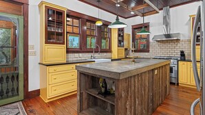 A kitchen with wooden cabinets, a central island, and a brick backsplash. - Grit&Grace Ranch - Private Resort Style Pool & Spa (Austin)