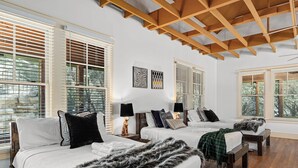 A hotel room with two beds, wooden beams, large windows, and artwork on the walls. - Grit&Grace Ranch - Private Resort Style Pool & Spa (Austin)