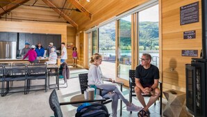A modern cabin with a wooden interior, large windows offering a view of the outdoors, a dining area, and a fireplace. - Pet-Friendly Mountain Escape | Private Firepit | Near Trails + Adventure (Silverthorne)