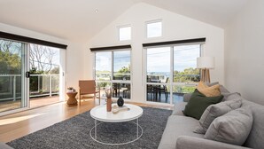 A spacious living room with a large window, a sofa, a coffee table, and a chair.