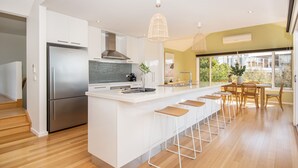 A modern kitchen with a central island, stainless steel appliances, and a dining area with a view.