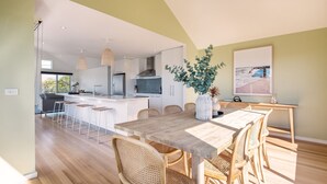 A modern kitchen with a central island, bar stools, and a dining table with chairs.