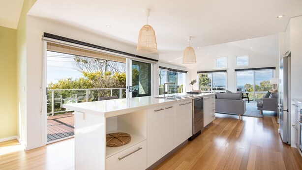 A modern kitchen with large windows, a balcony, and a view of the outdoors.