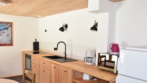 Eine kompakte Küche mit Holzschränken, einem eingebauten Geschirrspüler, einer Kaffeemaschine und einem Kühlschrank.