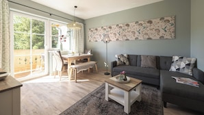 Un salon comprenant un canapé, une table basse, une table à manger avec des chaises et une grande fenêtre.