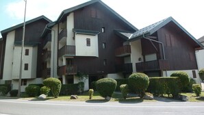 A multi-story building with balconies, a flat roof, and a well-maintained lawn. - Cozy studio in village center, pets allowed, private parking (Samoëns)