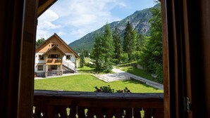 Una cabana de fusta amb un balcó, vista a la muntanya i un jardí ben cuidat.