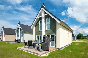 Une maison moderne dotée d’un patio aménagé avec du mobilier d’extérieur et un espace salon couvert.