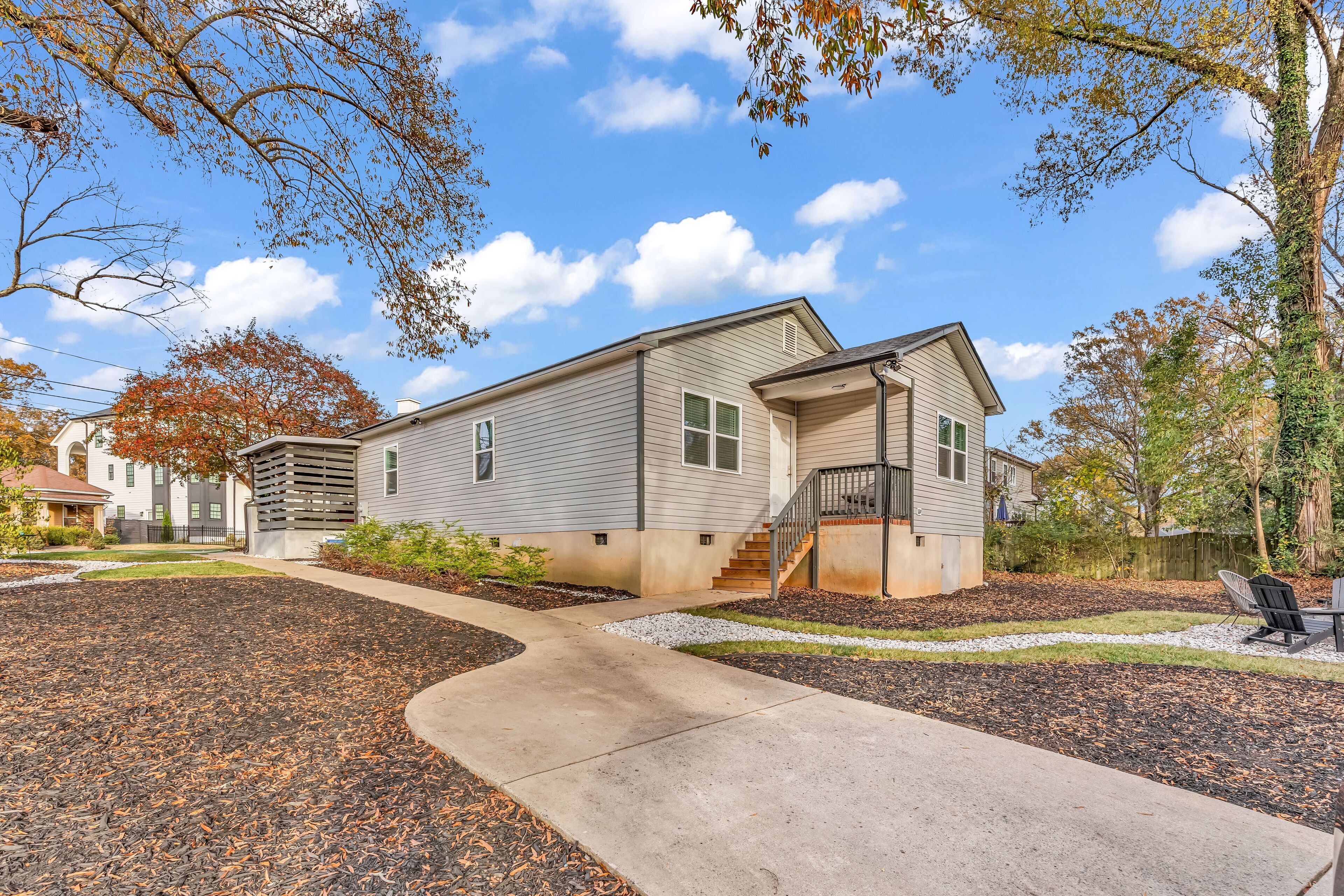 A two-story house with a front porch, a driveway, and a backyard with a grill.