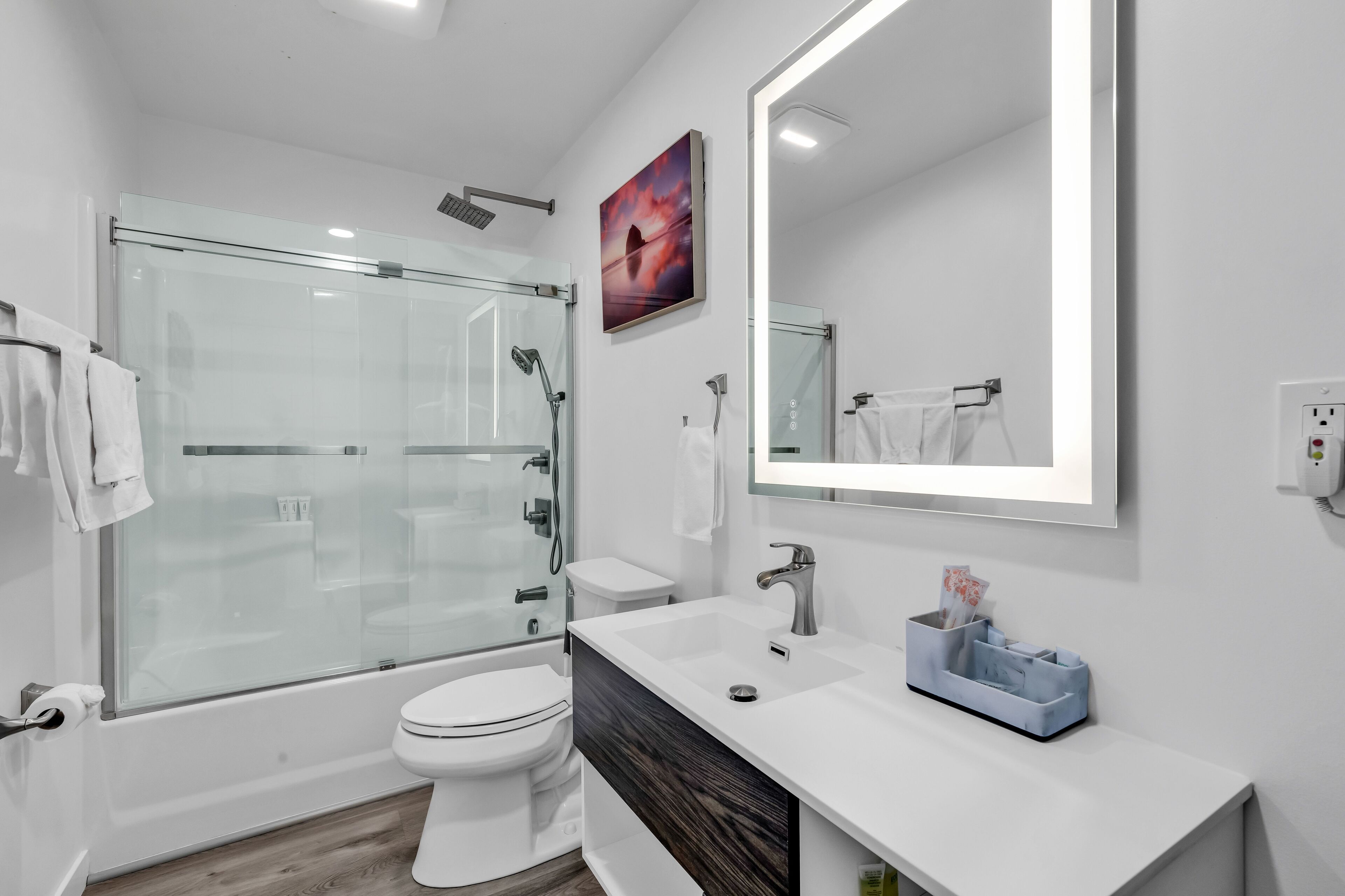 Un baño moderno con ducha envuelta en vidrio, inodoro blanco y tocador con espejo.