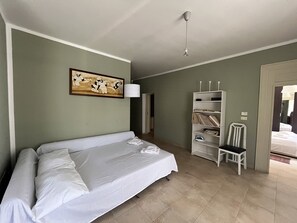 Une pièce comprenant un lit, une chaise, une bibliothèque et un tableau accroché au mur.