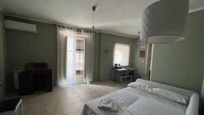 A bedroom with a bed, a desk, a chair, a radiator, and a window with curtains.