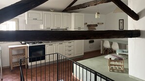 A kitchen with white cabinets, a gas stove, and a hanging light fixture.