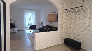 A living room with a sofa, a black chair, a hanging light fixture, and a patterned wallpaper. - "Lichtenegg" apartment with garage in Merano (Merano)