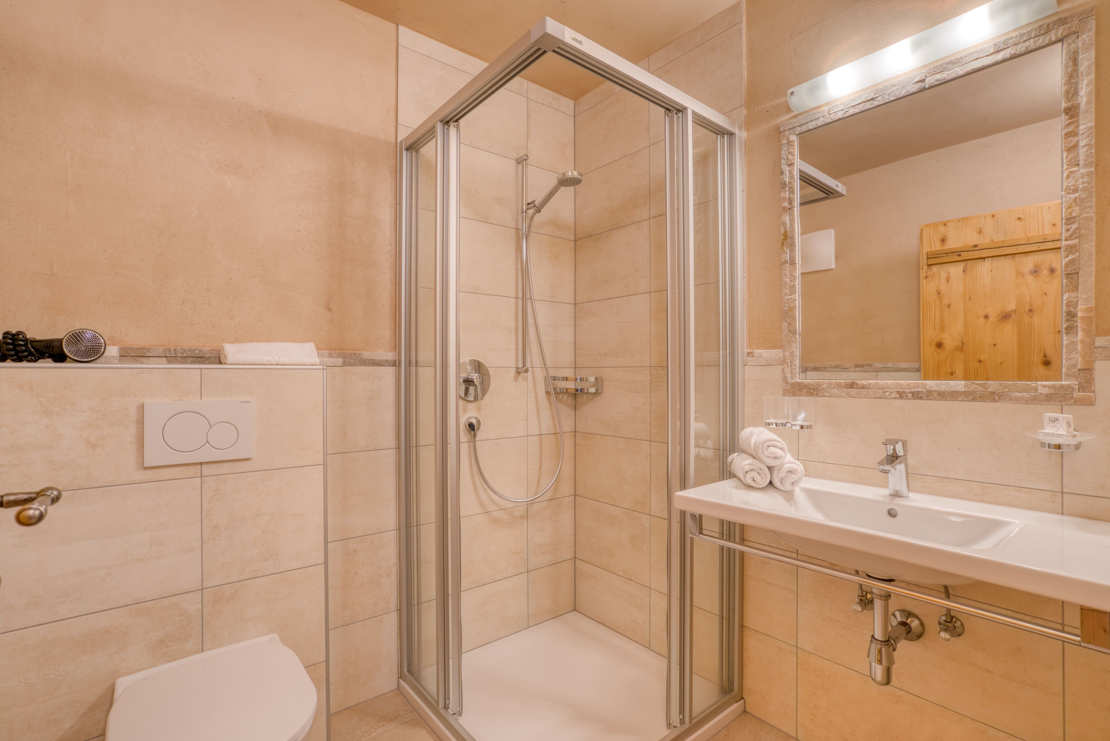 A modern bathroom with a glass-enclosed shower, a white sink, and a wooden cabinet.