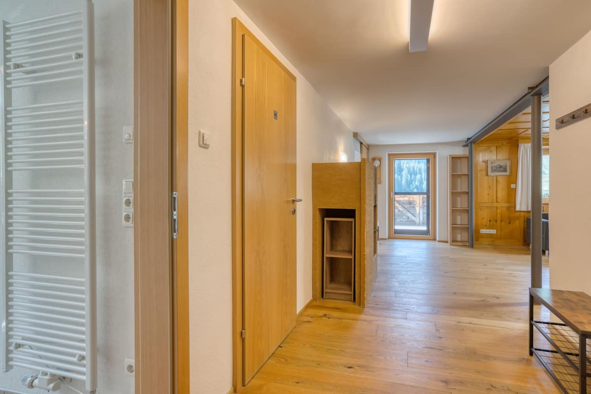 A hallway with wooden doors, a radiator, and a view of a room with a window.