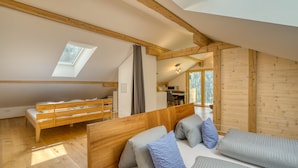 A cozy loft bedroom with a sloped ceiling, wooden beams, a skylight, a bunk bed, and a desk area. - HUS 24 (Schroecken)