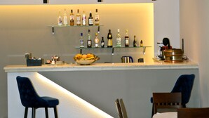 A bar area with a counter, bar stools, and shelves of bottles. - Hotel Marily (Pyrgos)