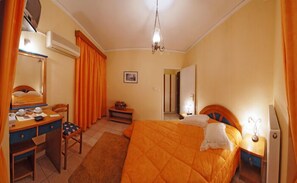A hotel room with a bed, a desk, a chair, a small table, and a mirror. - Hotel Marily (Pyrgos)