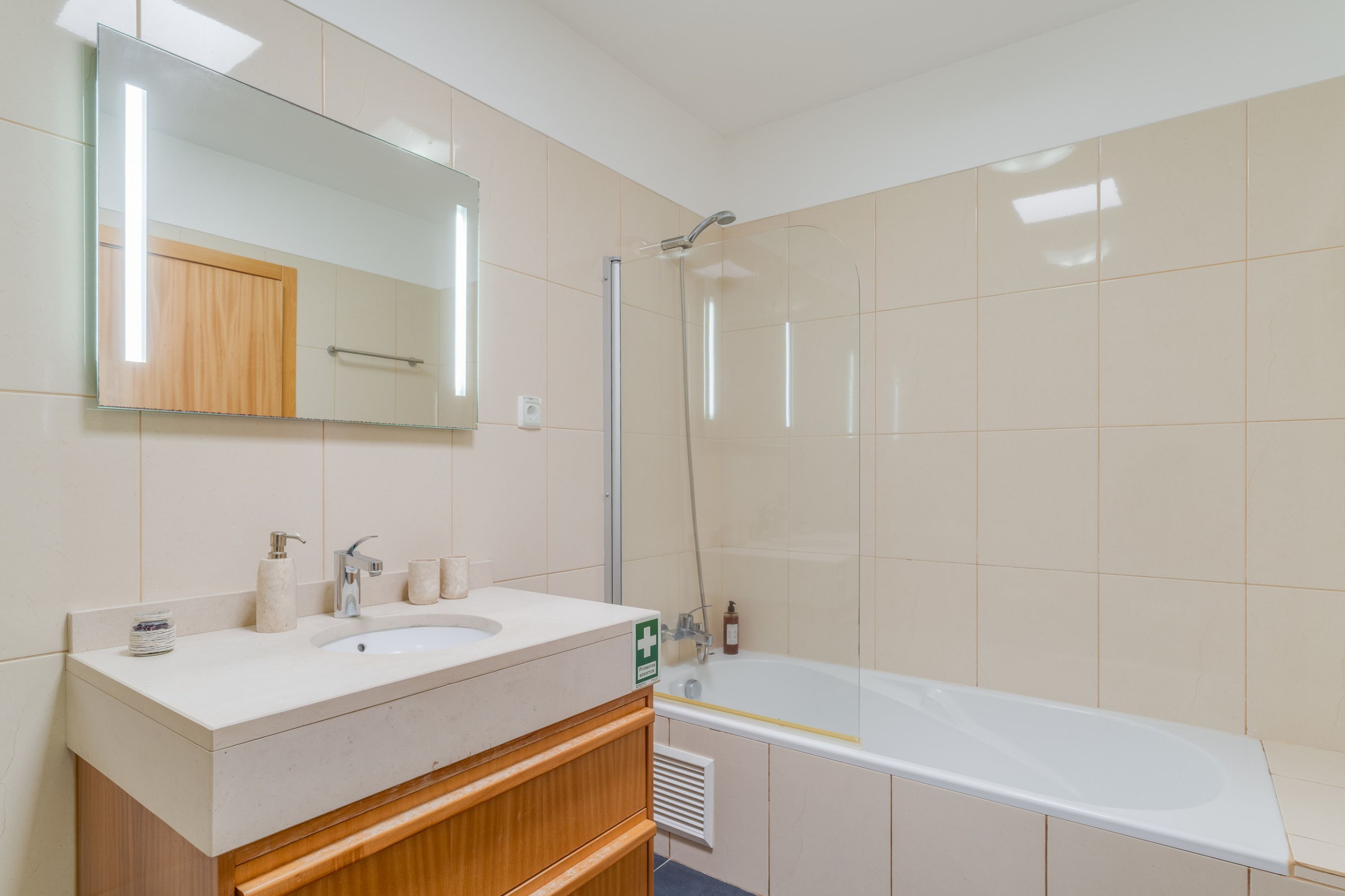 A bathroom with a white sink, mirror, and bathtub.