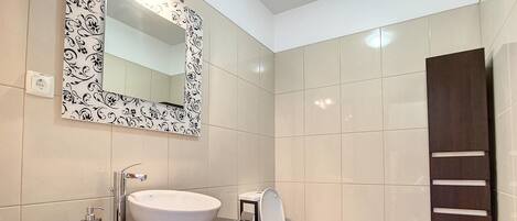 A modern bathroom with a large white sink, a toilet, and a mirror with a decorative frame.