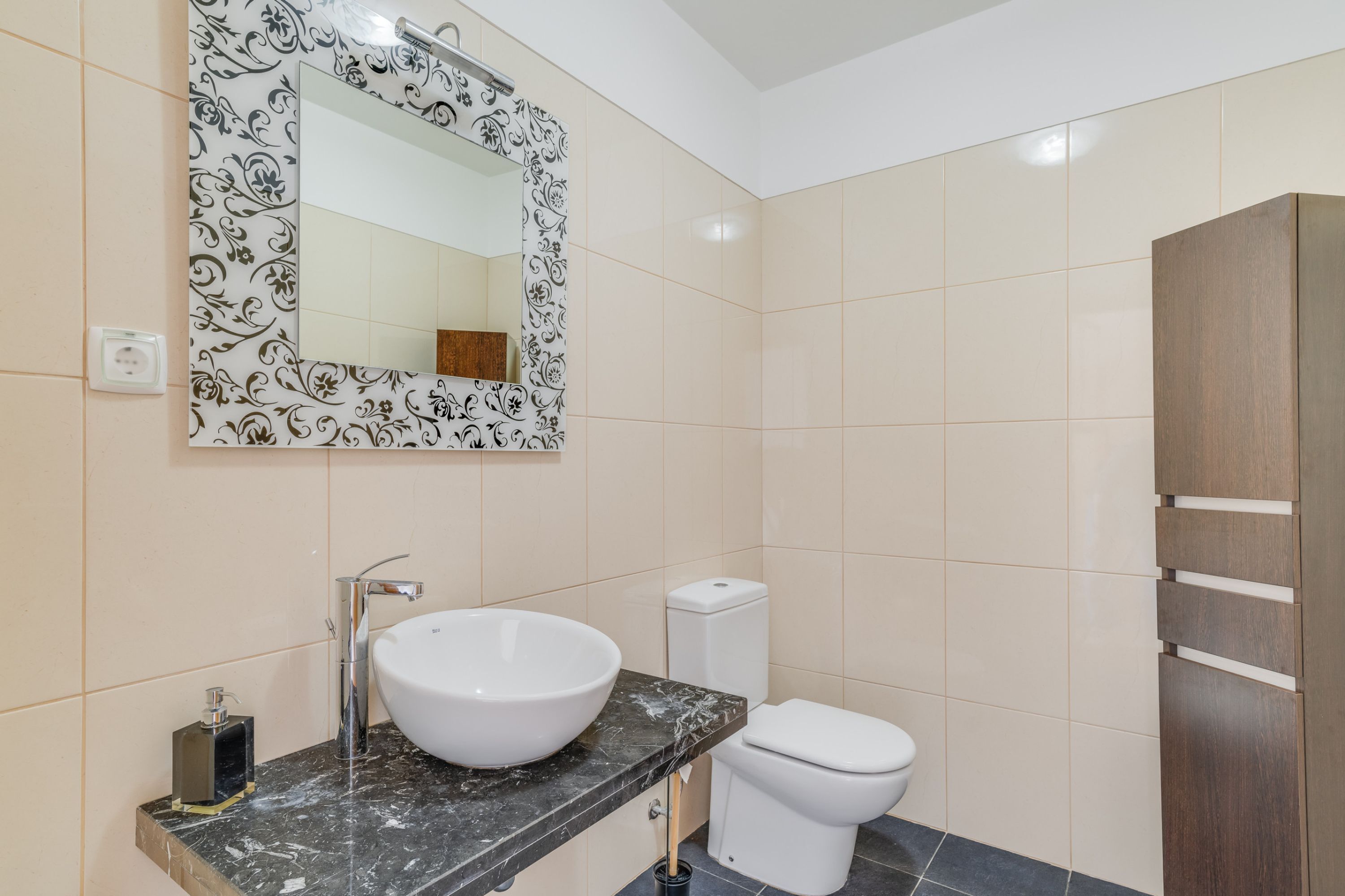 Une salle de bain avec un lavabo blanc, des toilettes et un meuble en bois.