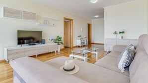 Un salon moderne avec un canapé, un téléviseur et une table basse en verre.