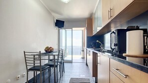 Une cuisine compacte avec un coin repas, un téléviseur à écran plat et une vue sur l’extérieur.