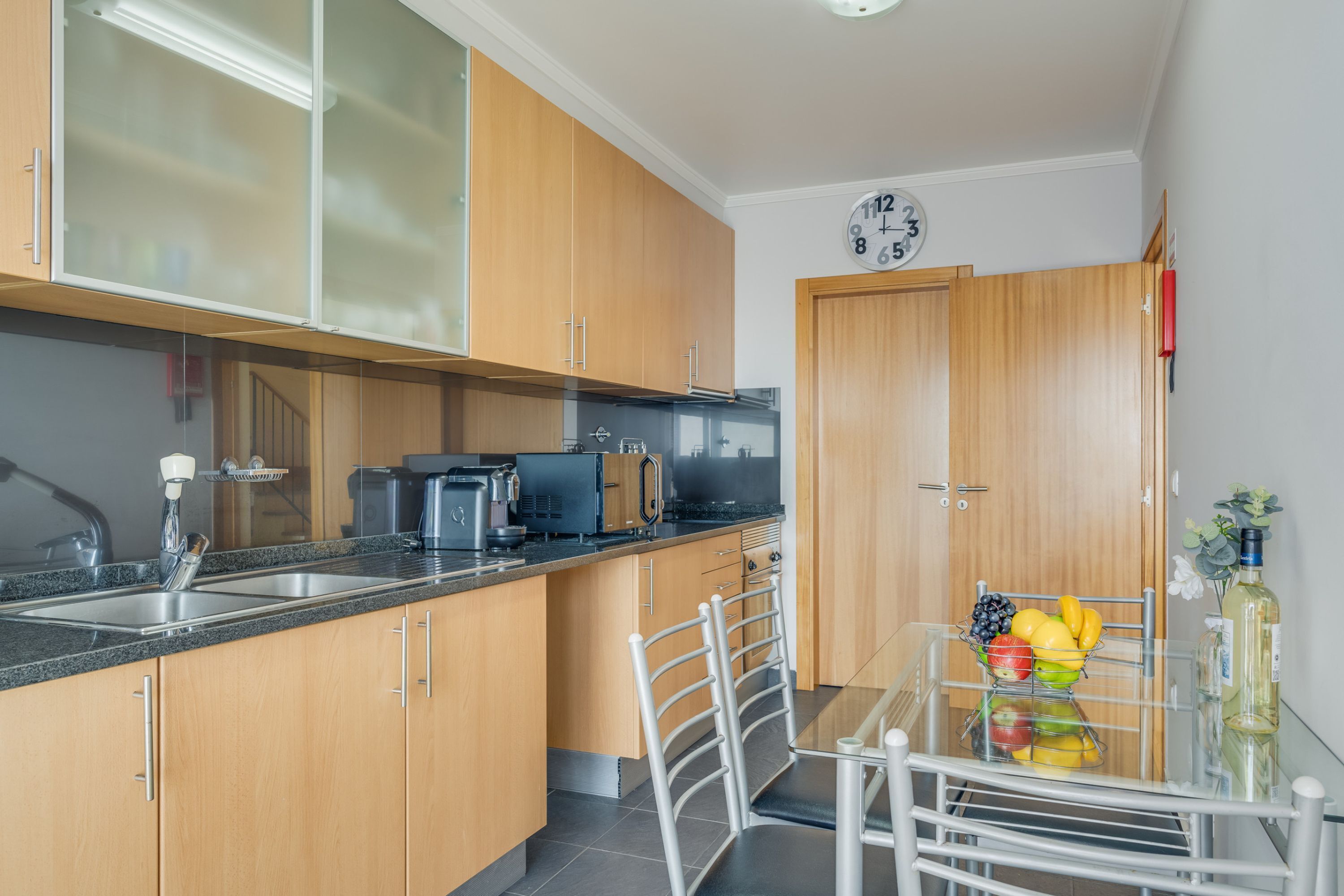 A modern kitchen with wooden cabinets, a black countertop, and a dining table with chairs.