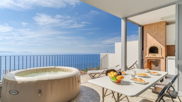 Un balcon avec un jacuzzi, une table garnie de nourriture et un four en briques.