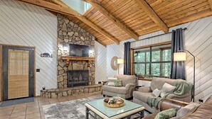 A cozy living room with a stone fireplace, leather sofas, and a large window.