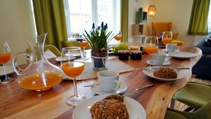 A breakfast table with orange juice, coffee cups, a plate of muffins, and a pitcher of orange juice. - Apartment "Blütezeit"- Ferienhof Gräfe restored 3-sided farm with pool & sauna (Meißen)